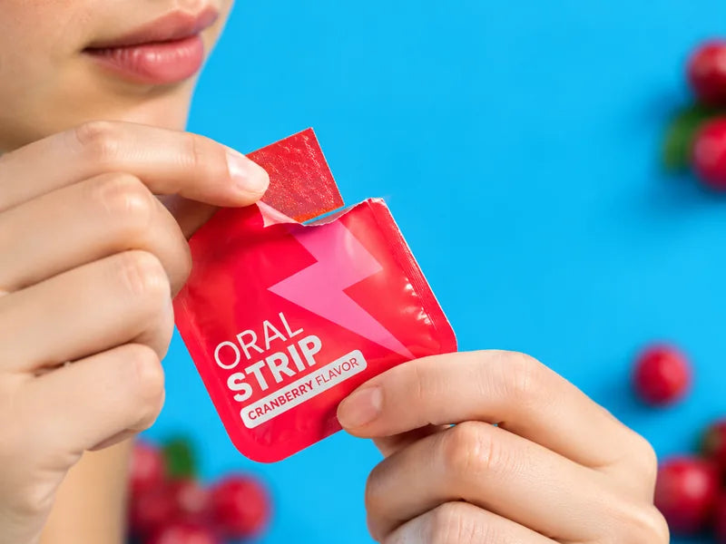 a hand tearing open a red ORAL STRIP sachet